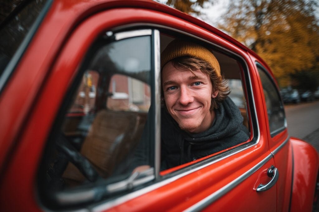 jonge man achter het stuur in rode auto
