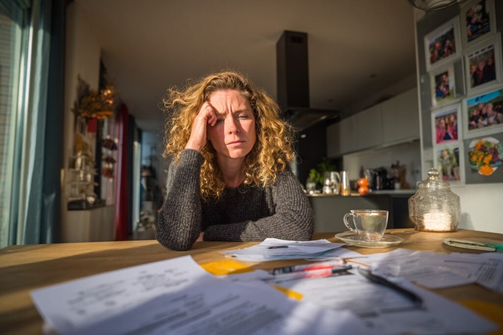 vrouw met stapel brieven rekeningen, stress, onduidelijk, onbetaald
